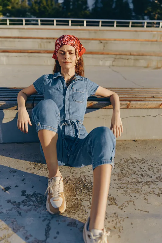 lifestyle woman in modern boho-western denim outfit relaxing outdoors in casual street style with film color tone and natural sunlight