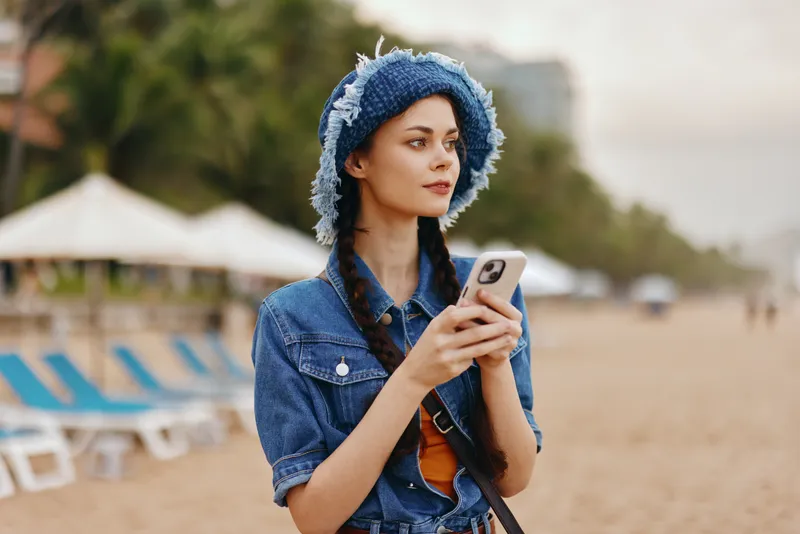 Стильная женщина наслаждается летом на пляже, делая селфи на телефон