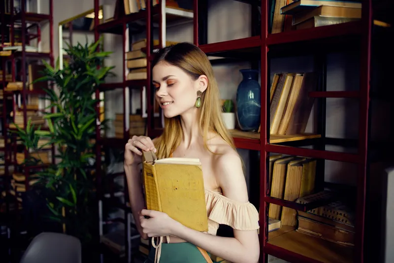 Красивая женщина с книгой в руках отдыхает в кафе