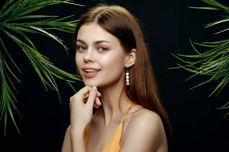 Женщина в купальнике на фоне экзотической тёмной зелени
