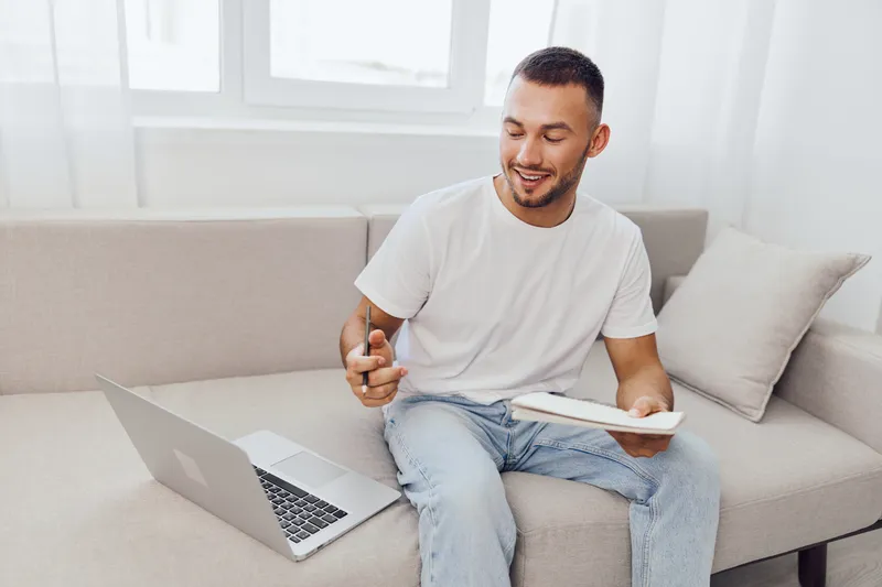 Smiling man in casual attire engaged in work from home, showcasing modern lifestyle and productivity. Focus on comfort and creativity in a bright environment.