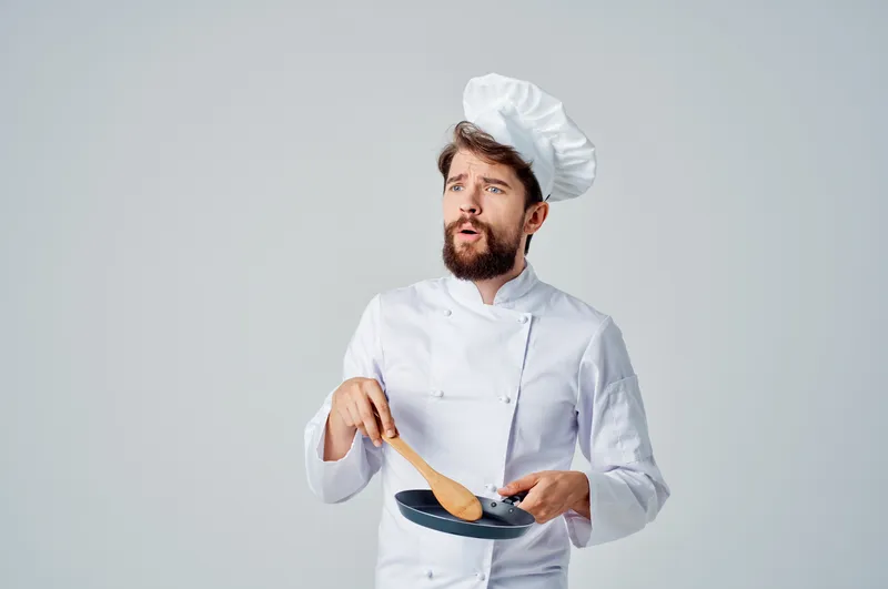 Мужчина-шеф-повар на кухне с кухонной утварью занимается приготовлением еды, что является его профессиональной работой