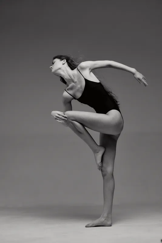 Black and white artistic woman dancer in a modern pose wearing a leotard with graceful movement and elegant style.