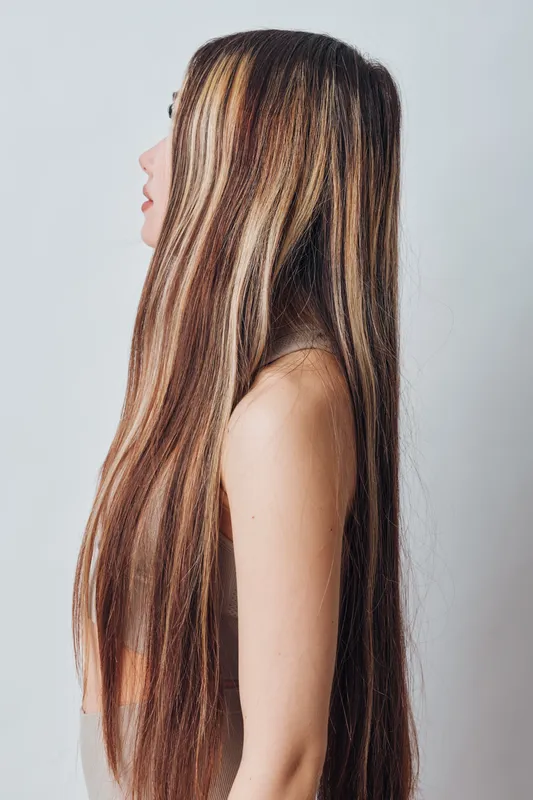 Woman with long straight hair in profile on white background, skin visible on shoulder, natural light illumination and side view portrait closeup.