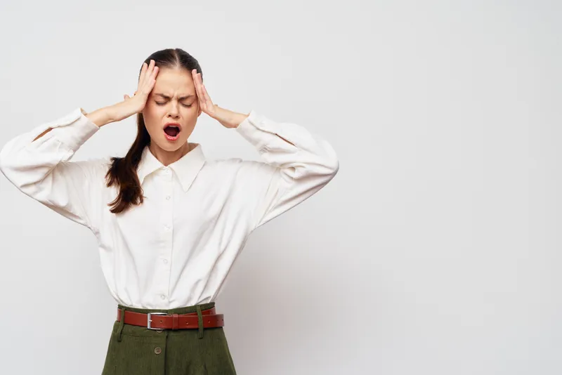 Стресс, головная боль, дискомфорт — на изображении молодая женщина, страдающая от головной боли