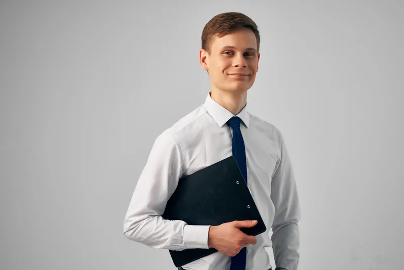 Менеджер в белой рубашке с галстуком, черная папка с документами, работа, позирование