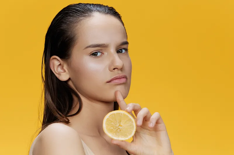 Брюнетка с лимоном возле лица, уход за чистой кожей, здоровье, крупный план, образ жизни