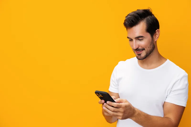 Мужчина указывает на смартфон с широкой улыбкой