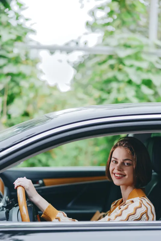 Car, driver, woman, smile a cheerful woman sits comfortably in the driver's seat with her hand confidently placed on the steering wheel, radiating joy and readiness for a journey