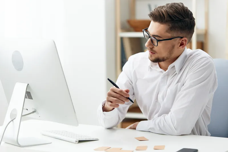 Менеджер работает за компьютером в интернете, излучая официальную уверенность в себе