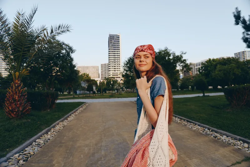 lifestyle woman in modern boho-western denim street style with bandana and crochet shawl captured in warm film color outdoors