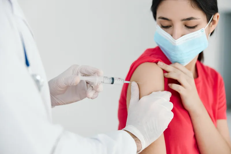 Врачи в больнице делают укол в плечо пациенту, крупный план