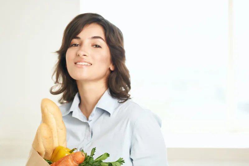 Брюнетка с букетом продуктов, овощами в супермаркете, на кухне, готовит