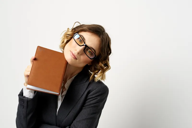 Женщина за работой с книгой в руке на светлом фоне