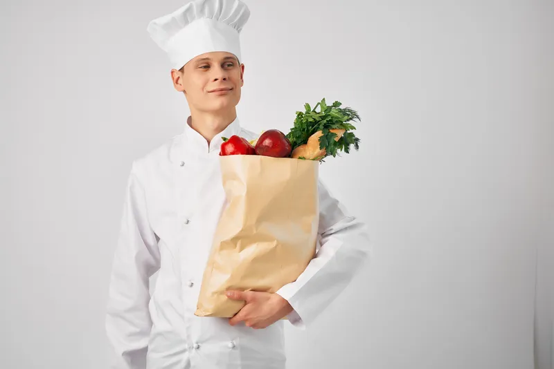 Шеф-повар готовит, держа в руках упаковку свежих продуктов