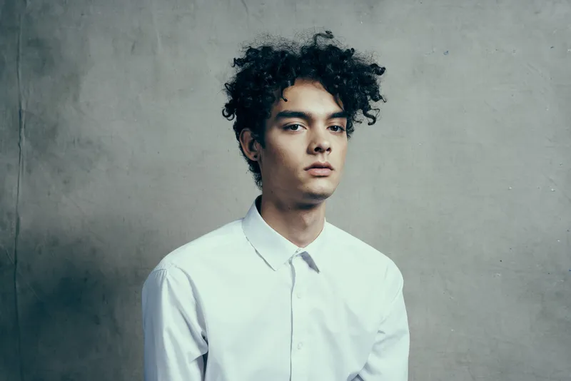 Мужчина с вьющимися волосами в белой рубашке, менеджер, в студии