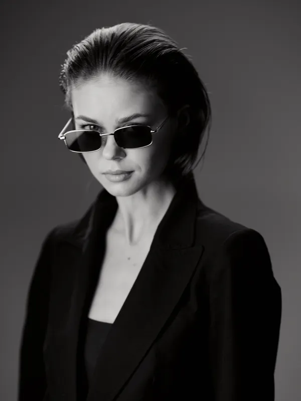Stylish woman wearing sunglasses in black and white portrait with serious expression and modern fashion attire