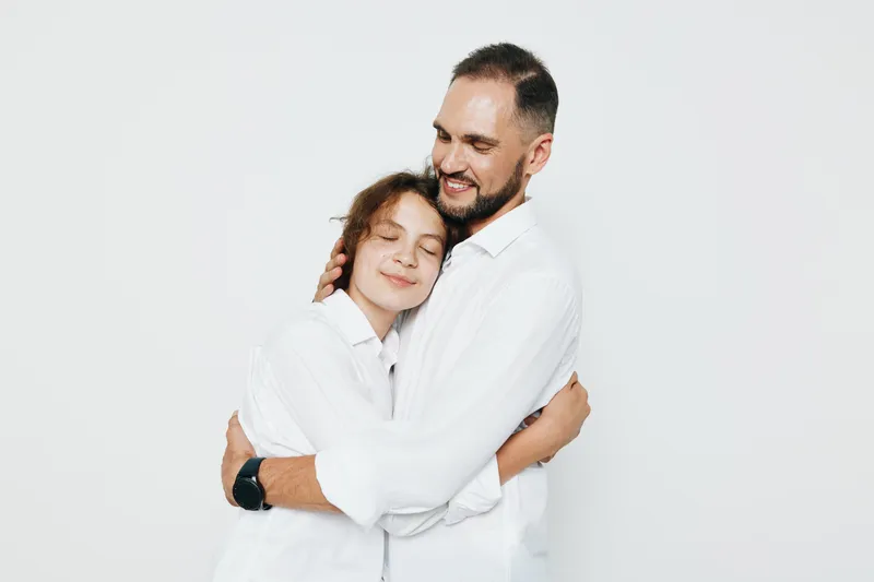 Isolated colored background features a professional man and a child in a warm embrace, conveying trust, care, and resilience in a corporate style scene.