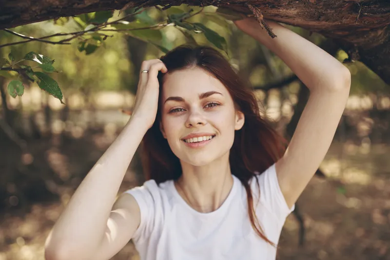 Женщина сидит возле дерева на фоне пейзажа
