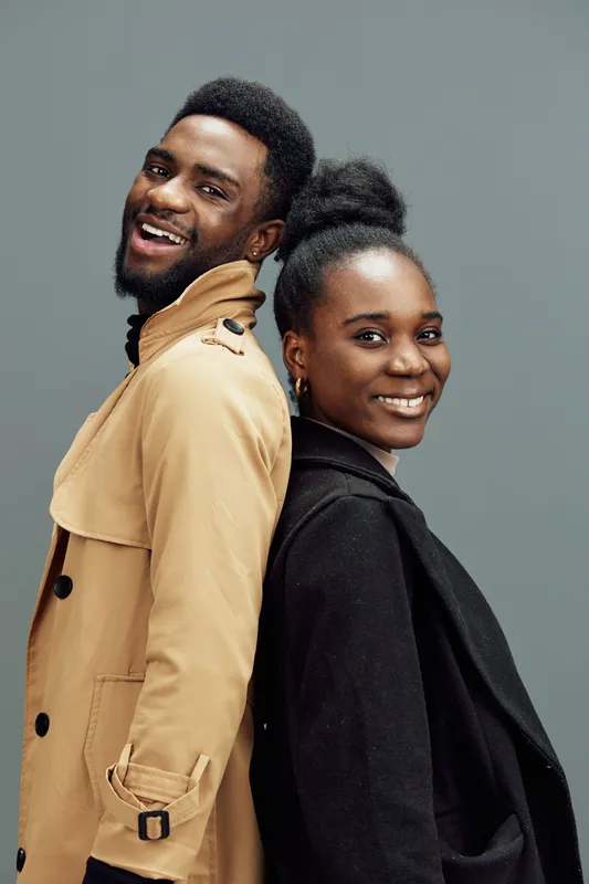 Happy young African couple smiling together, showcasing strong connection in modern fashion with neutral background
