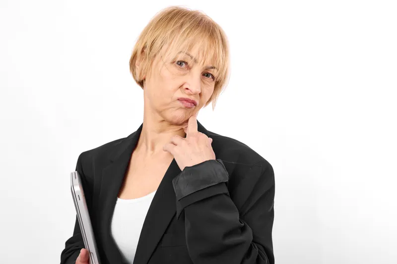 Senior woman portrait, thoughtful worried expression, holding a book, studio white background, calm isolation concept, aging education and learning today
