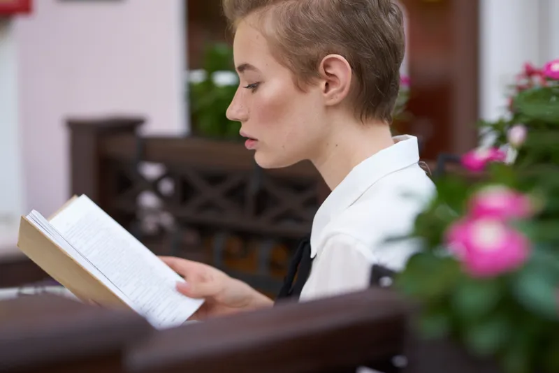Студент с книгой в руках читает на ходу, наслаждаясь свежим воздухом