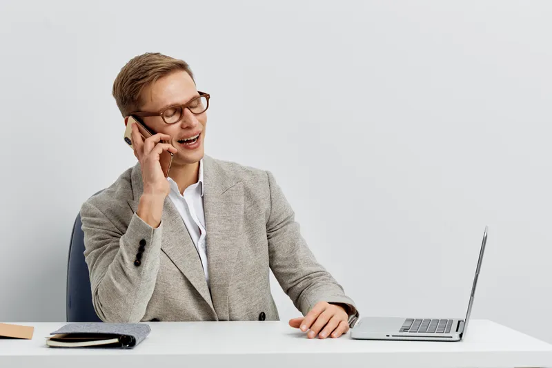 smiling man talking smartphone working laptop modern office casual wear business communication digital nomad concept