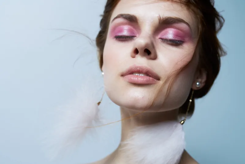 Красивая женщина с закрытыми глазами, пушистыми серьгами, косметикой и роскошными украшениями