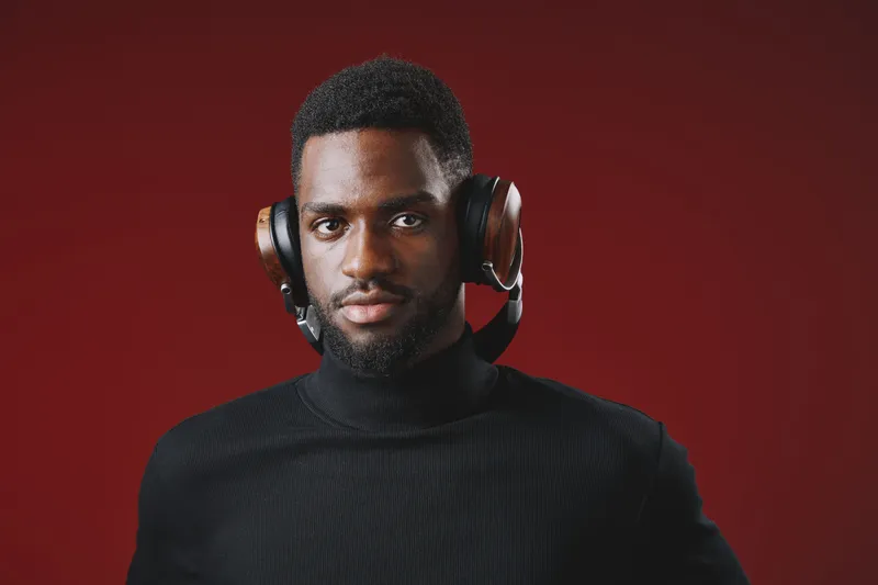 Stylish African man in black turtleneck wearing vintage headphones against a red background, exuding confidence and passion for music