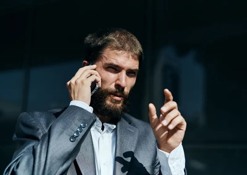 Деловой мужчина в костюме разговаривает по телефону на улице