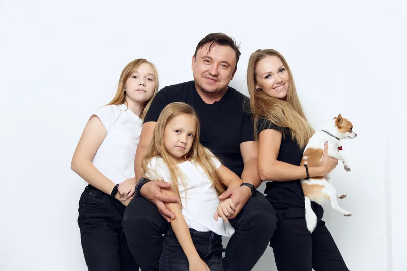 Муж с женой и детьми обнимаются во время семейной фотосессии