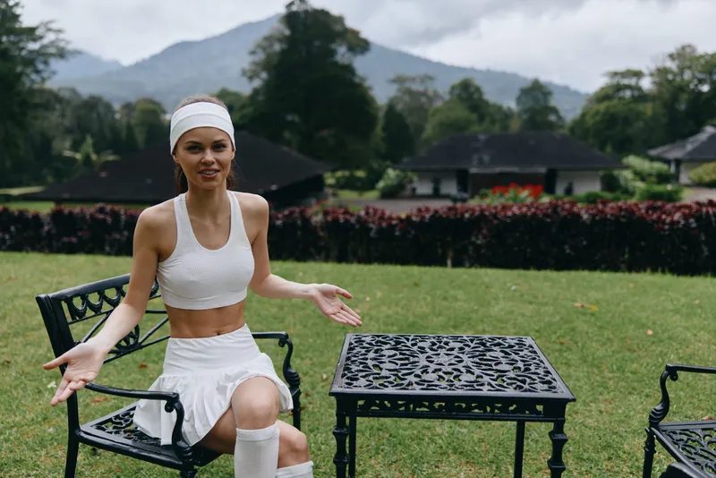 Young athletic woman in sportswear expressing joy outdoors, surrounded by lush greenery and mountains, embodying a healthy lifestyle and fitness concept