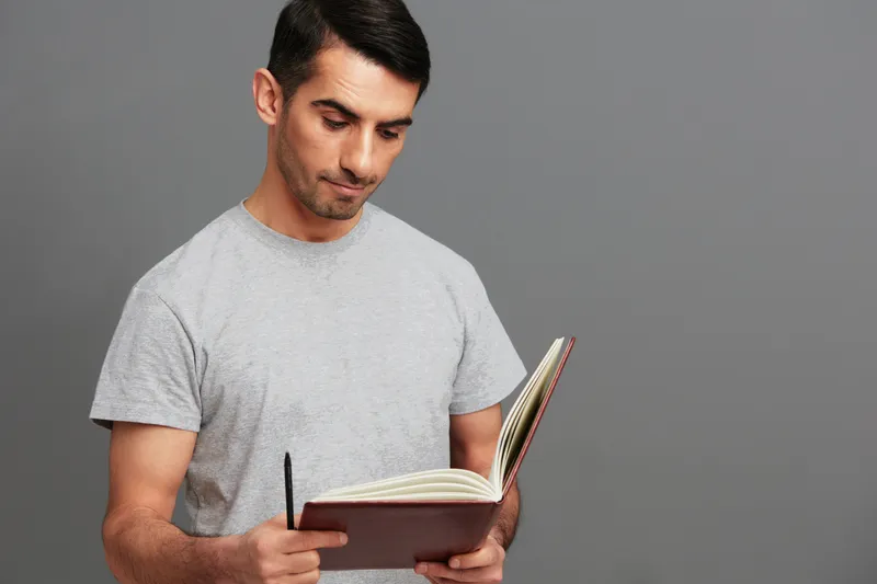 Красивый мужчина с книгой в руках, в серой футболке