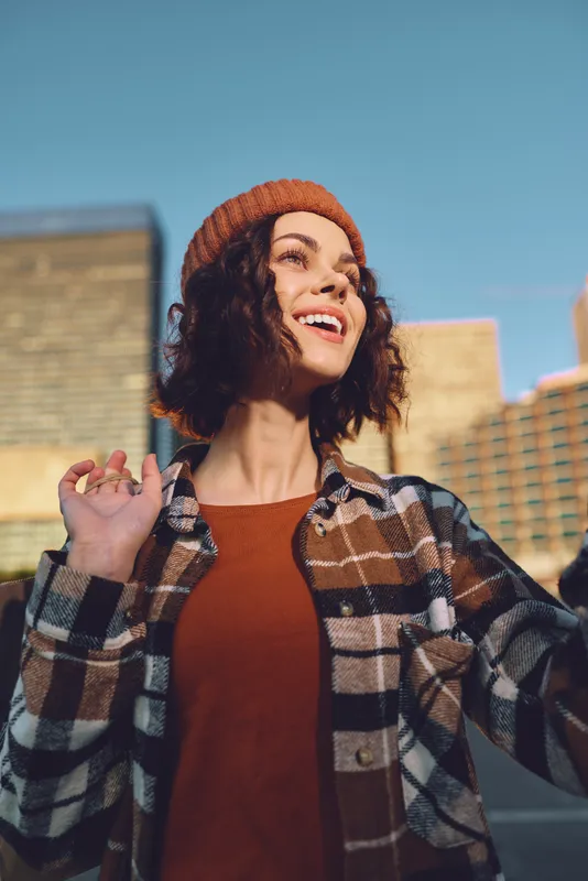 Woman smile in urban portrait at golden hour, candid lifestyle capture with authenticity and joyful expression, golden hour glow and mindful living vibe, emotional storytelling in modern city fashion.