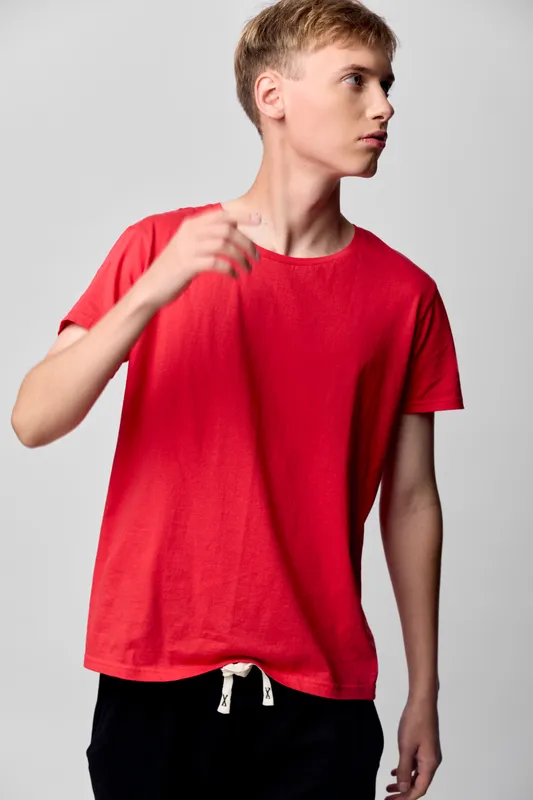 Red shirt, casual wear and streetwear vibe worn by a young man in a studio with a front pose, minimalist background, soft fabric, and comfortable fit for everyday style and contemporary fashion