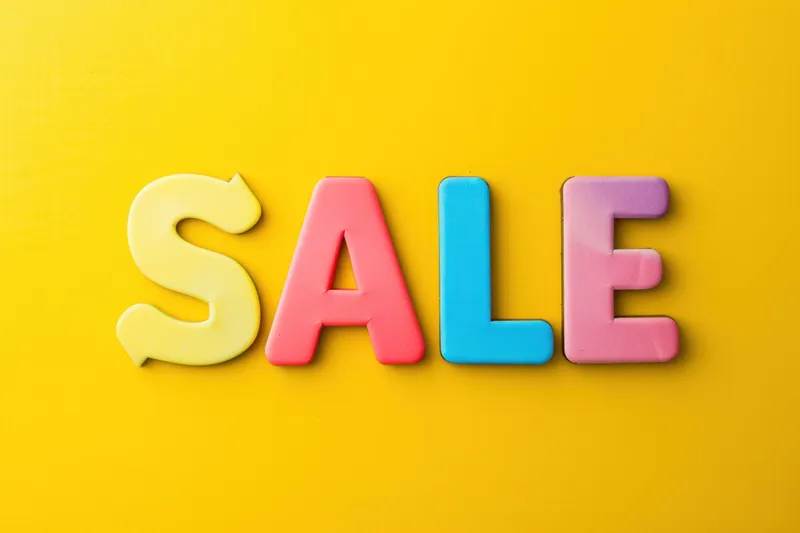 Трехмерный дизайн с разноцветными пластиковыми буквами sale на желтом фоне