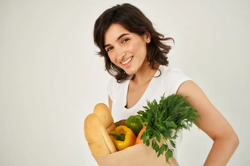 Весёлая брюнетка с пакетом продуктов