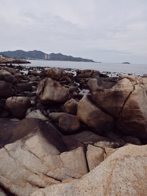 Serene rocky coastline with calm waters and distant mountains, perfect for tranquil nature scenes and landscape photography