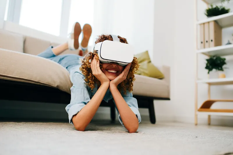 Виртуальное развлечение: счастливая женщина в VR-очках наслаждается футуристической киберигрой дома