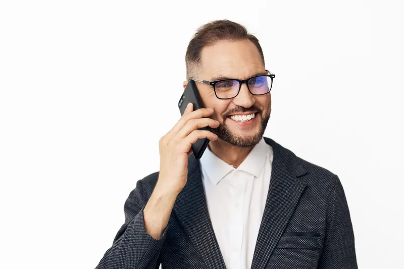 A professional business man on a solid colored, isolated background, expressing confident emotions while talking on a phone, conveying focus, energy, and clear communication.