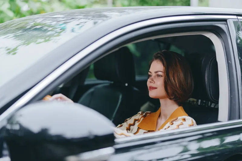 Car, driver, woman, cheerful smile fills the scene as the woman sits in the driver's seat, hands on the steering wheel, radiating confidence and readiness for travel.