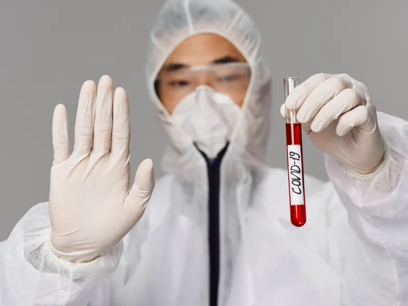 Мужчина держит в руках вакцину от COVID-19, что символизирует лечение, здоровье, лабораторию и науку