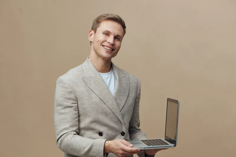 Smiling man working with laptop show cybersecurity concept hold open notebook beige background casual jacket technology usage business