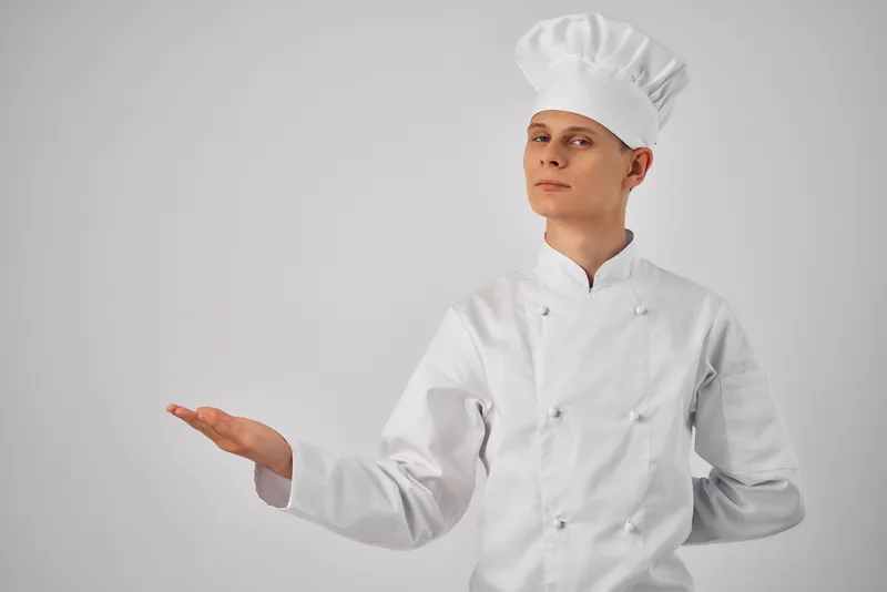 Мужчина в униформе повара жестикулирует рукой, профессиональная работа по приготовлению пищи