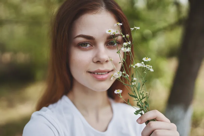 Жизнерадостная женщина среди полевых цветов на природе