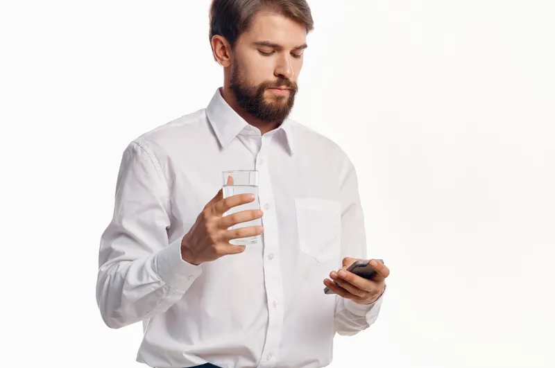 Бородатый мужчина пьет воду на изолированном фоне