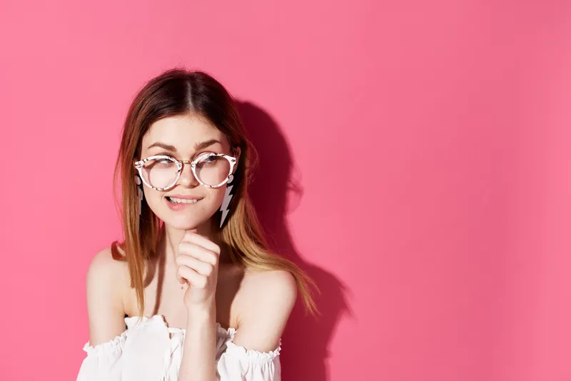 Симпатичная женщина в модных очках, с серьгами и украшениями, роскошь и веселье на розовом фоне