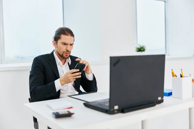 Руководитель работает с документами в офисе, держа в руке телефон
