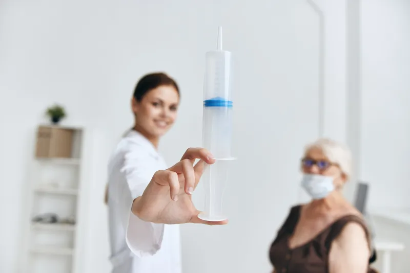 Медсестра делает укол пожилой женщине, вакцинация для защиты иммунитета