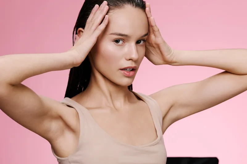 Young woman with long hair on pink background demonstrating skincare routine and healthy skin care concepts, expressing confidence and wellness
